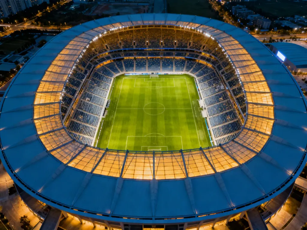 Widok z lotu ptaka na oświetlony Stadion Narodowy z widoczną murawą i pustymi trybunami o symetrycznym układzie.